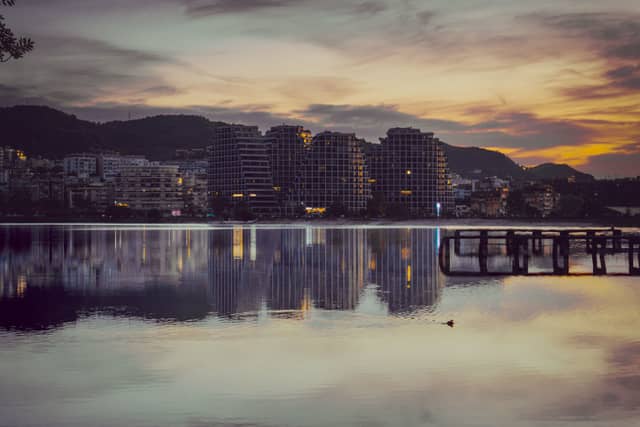 New apartment blocks reflected in still water at dusk on the Albanian coast